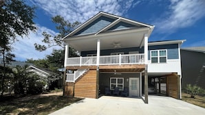 Ein zweistöckiges Haus mit Balkon, überdachter Terrasse und Garage.