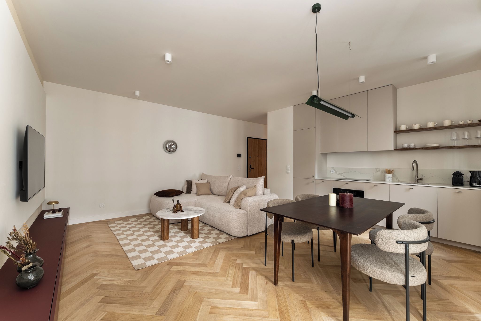 Un espacio de estar moderno con comedor, cocina y un televisor de pantalla plana montado en la pared.