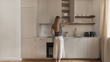 A woman in a kitchen with a built-in oven, a coffee maker, and a kettle on the counter.