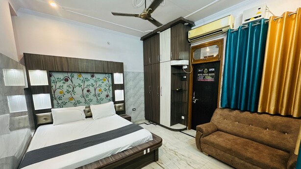 Habitación de hotel con cama, sofá, ventilador de techo, armario y puerta con un cartel.