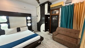 Una habitación de hotel con cama, ventilador de techo, armario, sofá y una puerta con un cartel.