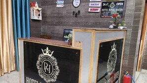 Un mostrador de recepción con un reloj y cuadros en la pared, un letrero de recepción y un extintor.