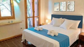 A hotel room with a bed, a window, a nightstand, and wall art. - La Villa sul Mare - Direct beach front access (Geremeas)