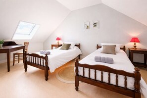 Ein Zimmer mit zwei Holzbetten, einem Schreibtisch, einem Stuhl, einem kleinen Tisch und einem runden Teppich.