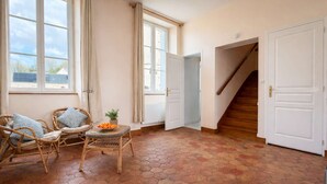 Ein Zimmer mit sechseckig gefliestem Boden, Korbmöbeln und einer Treppe, die zu einer weiteren Ebene führt.