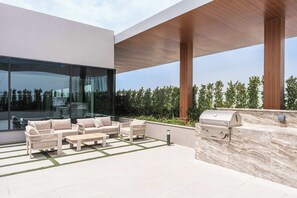 Une terrasse extérieure moderne, aménagée avec des sièges, un barbecue et offrant une vue sur la ville.