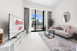 A modern living room with a large TV, a sofa, a coffee table, and a view of the outdoors. - Free housekeeping visits during your stay - StayShort - Comfortable Studio Stay in Arjan Sleeps 2 with  Balcony (Arjan)
