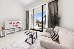 A modern living room with a sofa, a coffee table, a TV, and a balcony with a view. - Free housekeeping visits during your stay - StayShort - Comfortable Studio Stay in Arjan Sleeps 2 with  Balcony (Arjan)