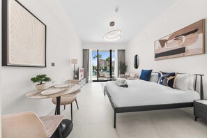 A modern hotel room with a bed, bedside table, and a dining area with a table and chairs. - Free housekeeping visits during your stay - StayShort - Comfortable Studio Stay in Arjan Sleeps 2 with  Balcony (Arjan)