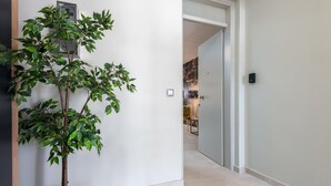 En hall med en krukväxt, en dörr som leder in till ett rum med en vägg av sten, och en ljusströmbrytare på väggen.