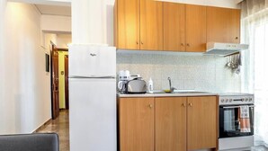 Una cucina compatta con mobili in legno, un frigorifero bianco, un tostapane e un forno.