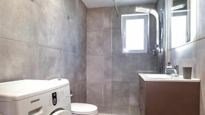 Un bagno con una lavatrice Samsung, un water, una doccia e un lavandino.