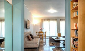A living room with a sofa, a coffee table, a dining table with chairs, and a bookshelf. - Rhodes Heart Suite, Apartment (Rhodes)