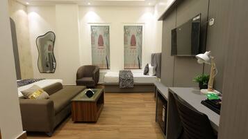 Una sala de estar moderna con un sofá, un sillón, una mesa de centro y un televisor montado en la pared.