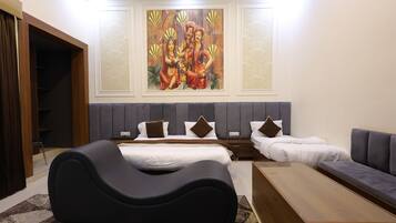 A modern hotel room with a large bed, a sofa, a unique black chair, and a painting on the wall.