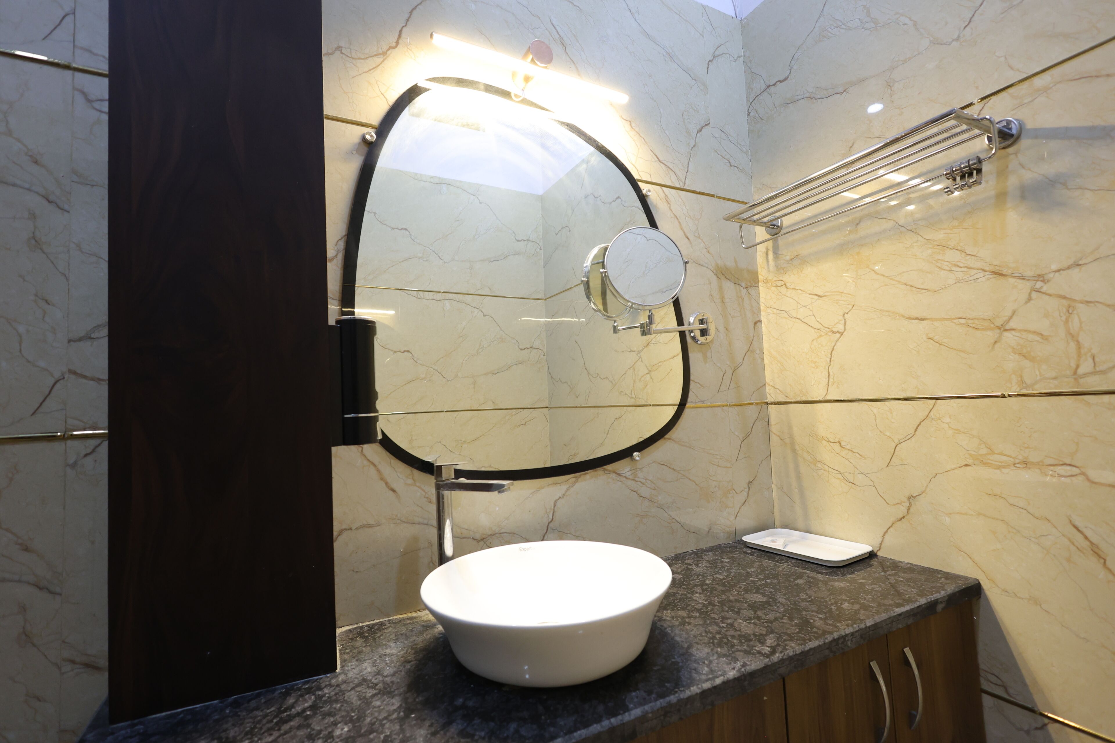 Un baño con lavamanos blanco, un espejo y un perchero para toallas.