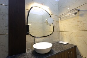A bathroom with a white sink, a mirror, and a towel rack. - Hotel Marina (Meerut)