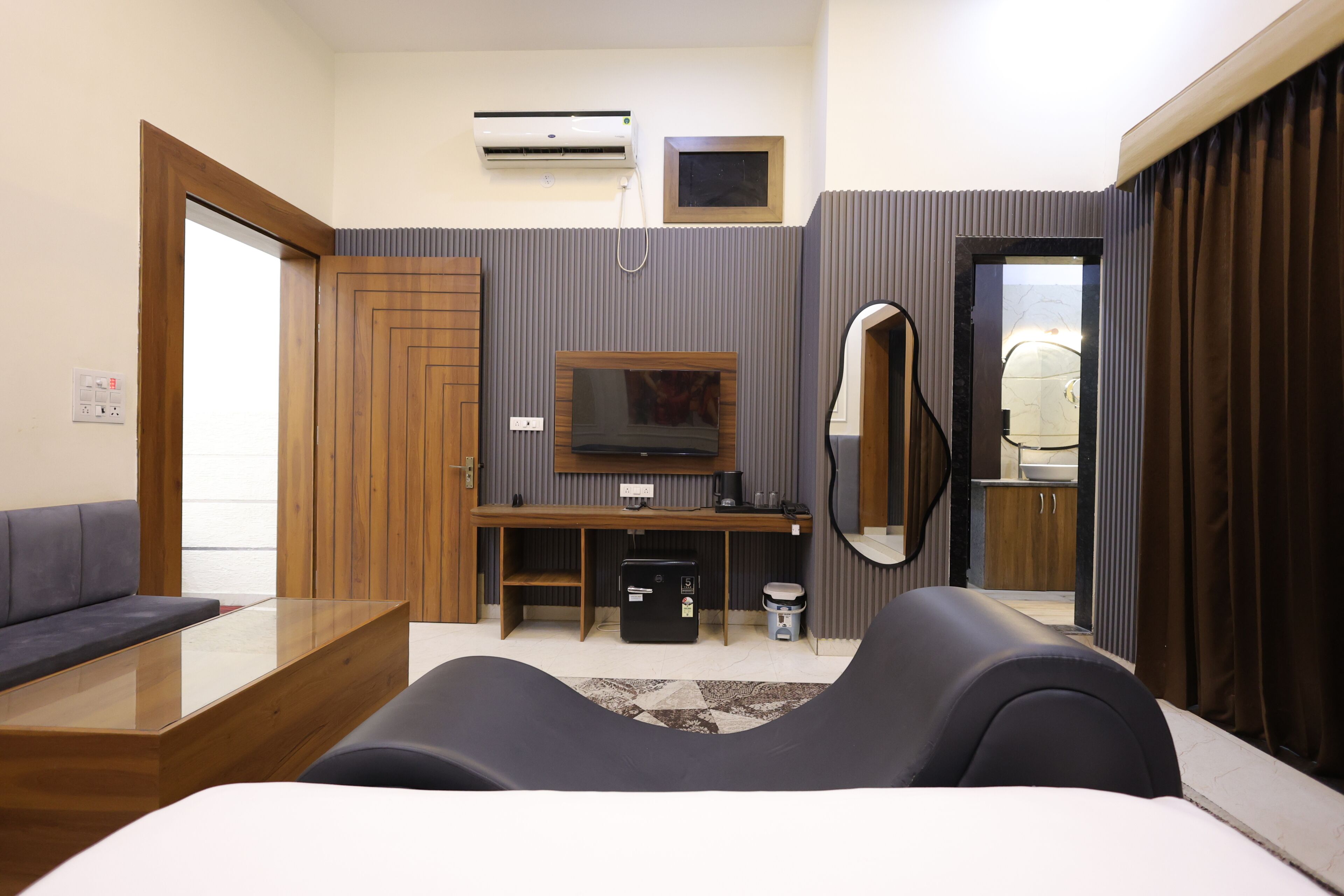 Una habitación de hotel con sofá, televisor, espejo, escritorio y armario.
