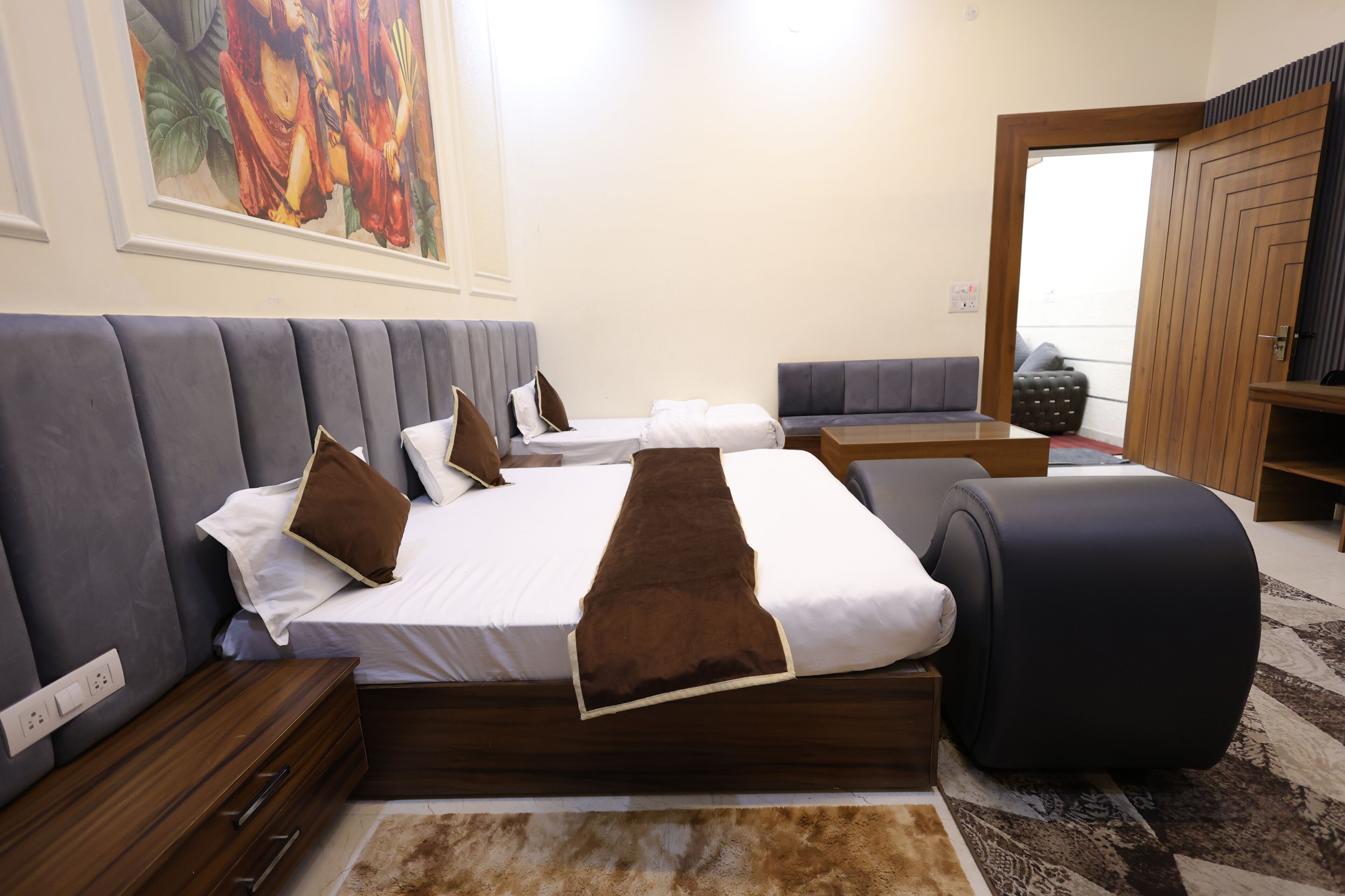 Una habitación de hotel con una cama grande, un sofá, una mesita y un televisor.