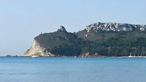 Paisaje costero con un imponente risco y mar tranquilo.