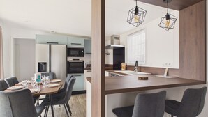 A modern kitchen with a dining area, featuring a central island, dark chairs, and pendant lighting. - Shared heated pool, accommodation for 6 (Saint-Gilles-Croix-de-Vie)