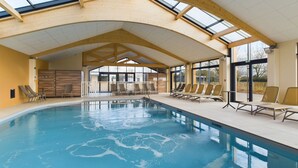 An indoor swimming pool with a high ceiling and skylights, surrounded by lounge chairs. - Shared heated pool, accommodation for 6 (Saint-Gilles-Croix-de-Vie)