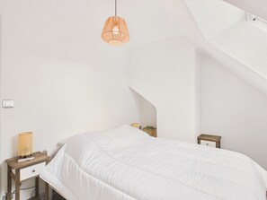 Un dormitorio con cama, mesita de noche, lámpara y lámpara colgante.