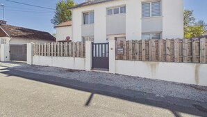 A two-story house with a gated driveway, a wooden fence, and a clear sky. - Beach 300m away, house 8 adults and 2 children (La Plaine-sur-Mer)