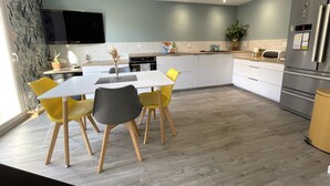 A modern kitchen with a dining area, a flat-screen TV, and a refrigerator. - Beach 300m away, house 8 adults and 2 children (La Plaine-sur-Mer)