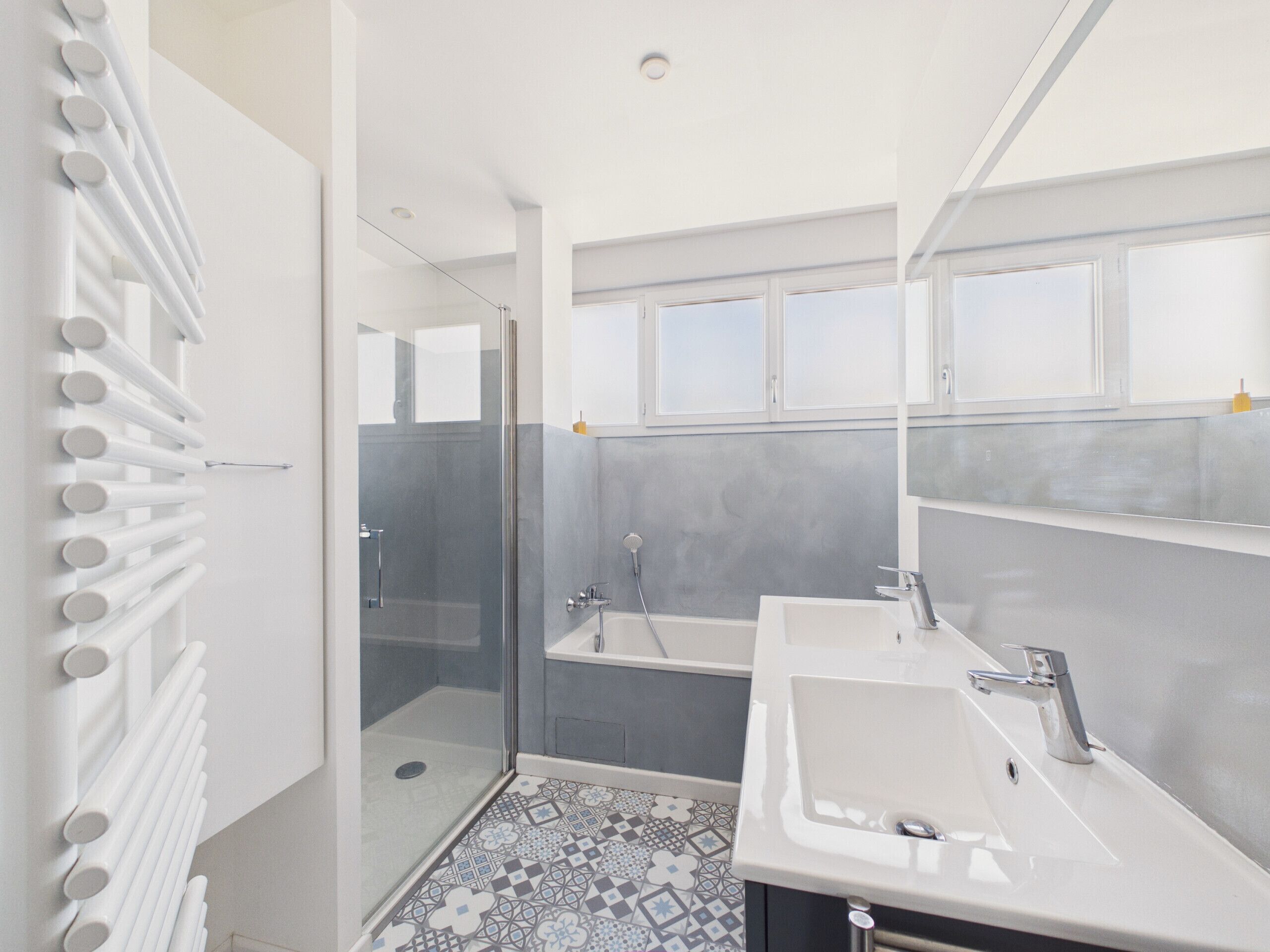 Une salle de bain moderne avec une douche, deux lavabos et un carrelage décoratif.