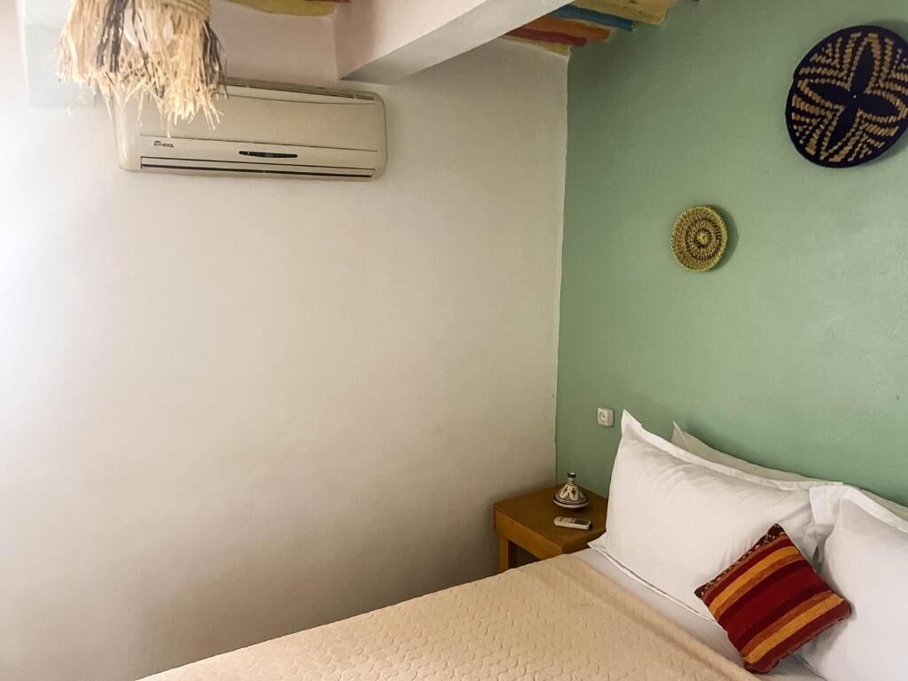Ein Schlafzimmer mit Bett, Nachttisch, Wand-Klimaanlage und einer Wanddekoration.
