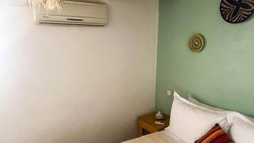 Ein Schlafzimmer mit Bett, Nachttisch, Wand-Klimaanlage und einer Wanddekoration.