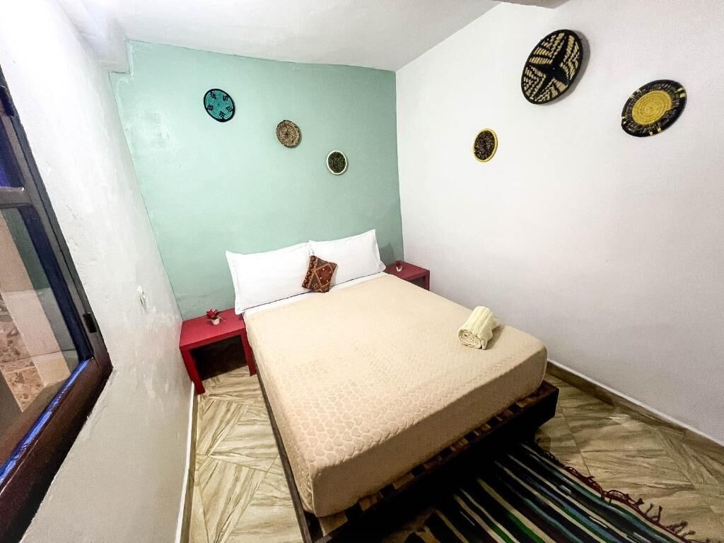 A room with a bed, a red nightstand, and decorative wall plates.
