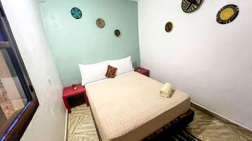 A room with a bed, a red nightstand, and decorative wall plates.