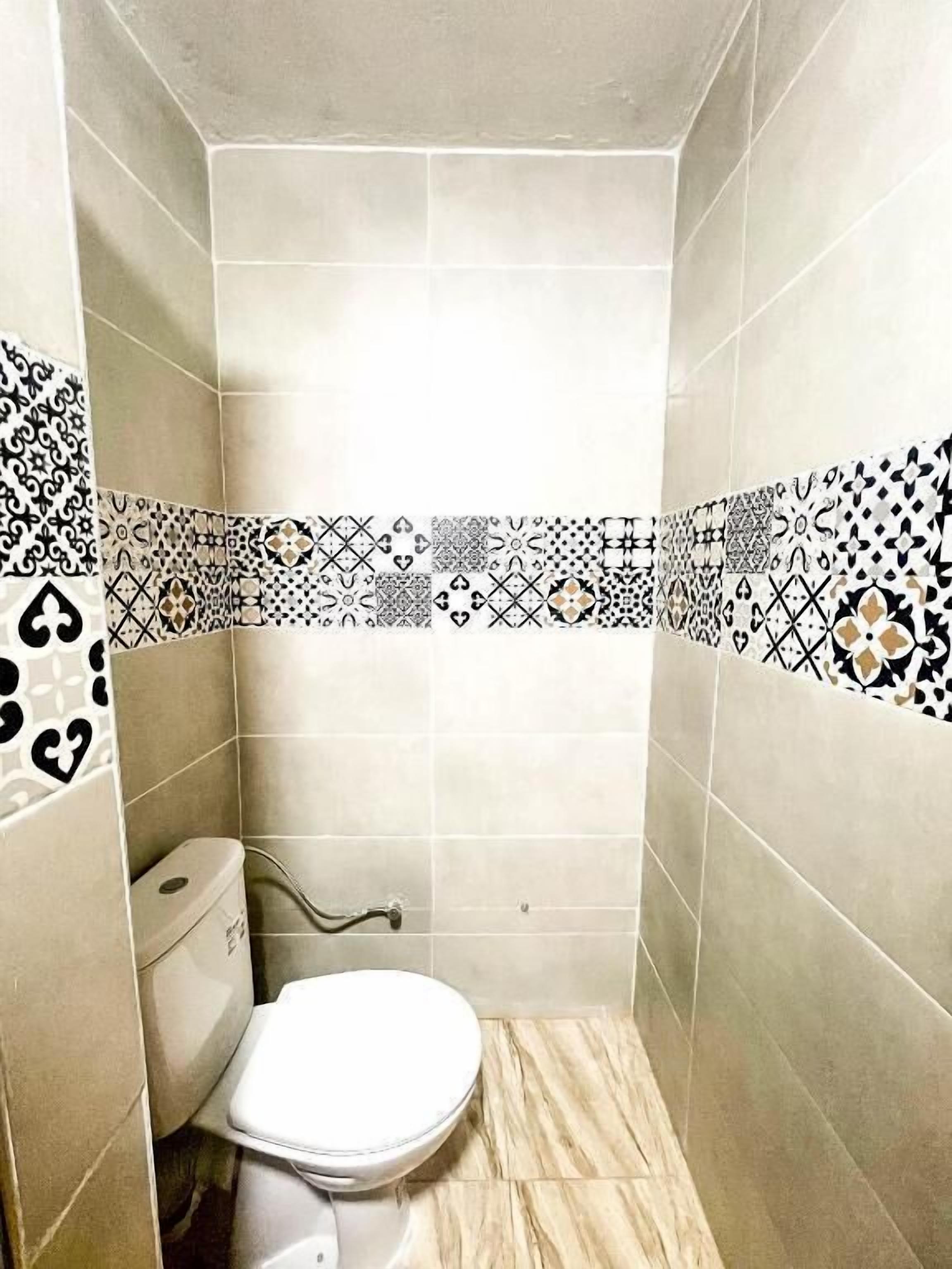 Ein kleines Badezimmer mit Fliesen, einer Toilette und einer Duschkabine.