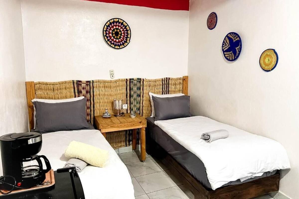 Una habitación con dos camas, cafetera y una mesita.