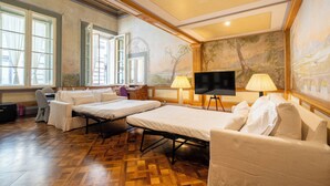 A hotel room with two beds, a TV, and a painting on the wall.