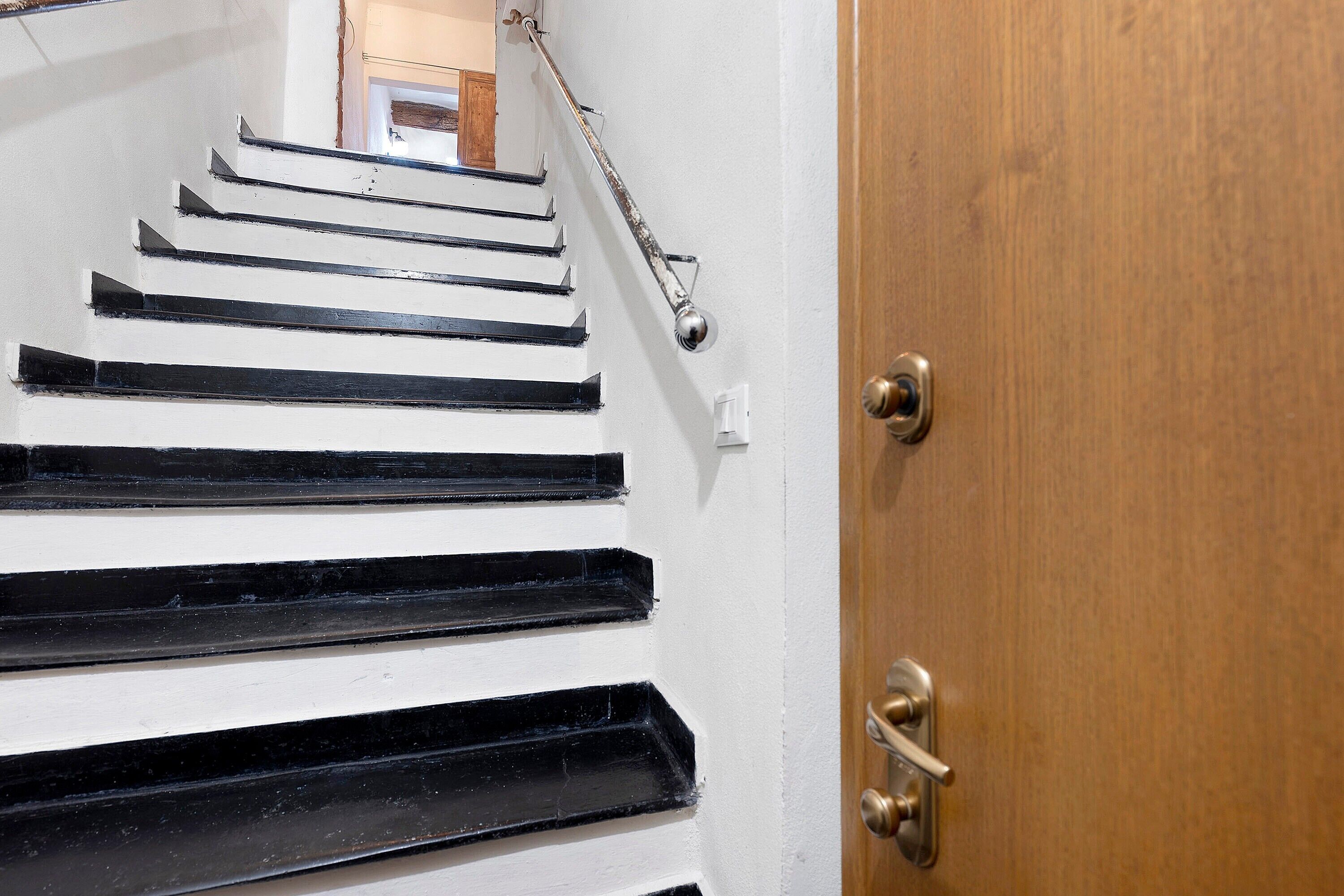 A staircase with black steps leading to a wooden door.
