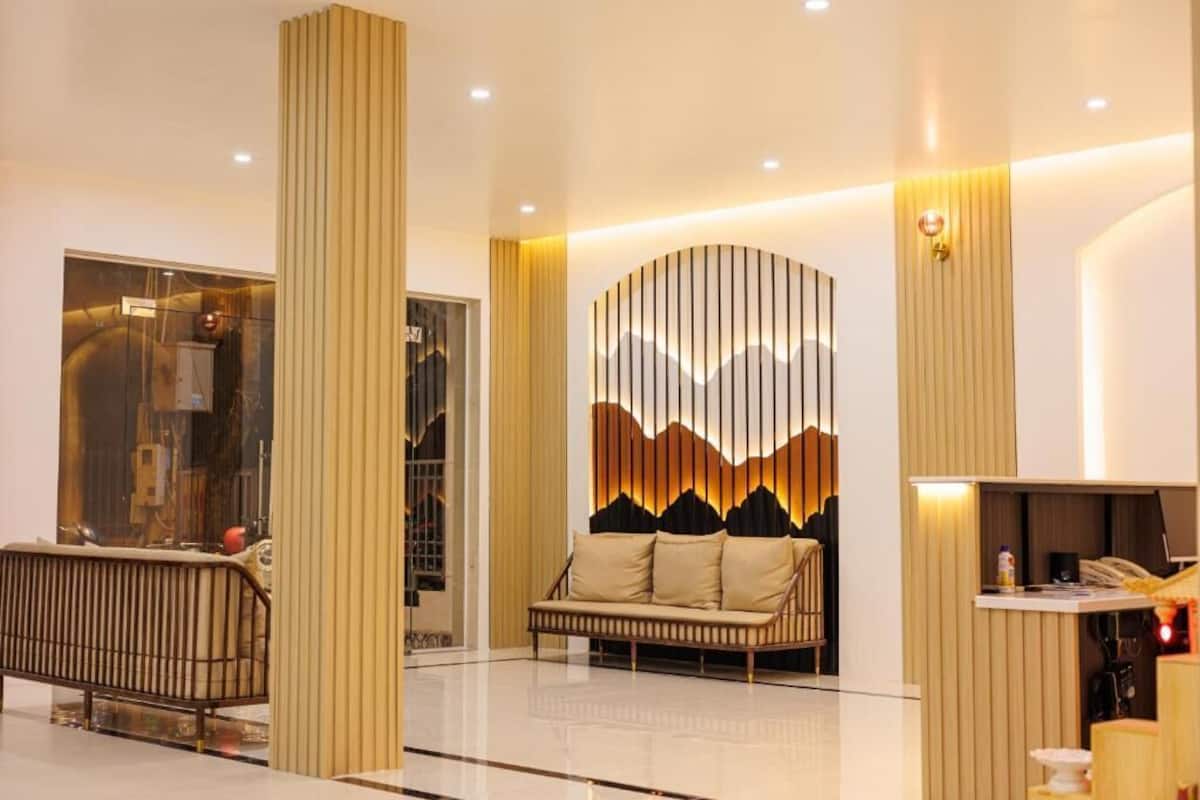 A modern lobby with a sofa, a reception desk, and a wall with vertical lines.