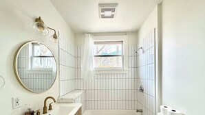 A bathroom with a bathtub, toilet, sink, and a window. - Downtown Brunswick 1st FL Sun Drenched With Porch (Brunswick)