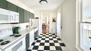 A kitchen with a checkered floor, a stove, a microwave, and green cabinets. - Downtown Brunswick 1st FL Sun Drenched With Porch (Brunswick)