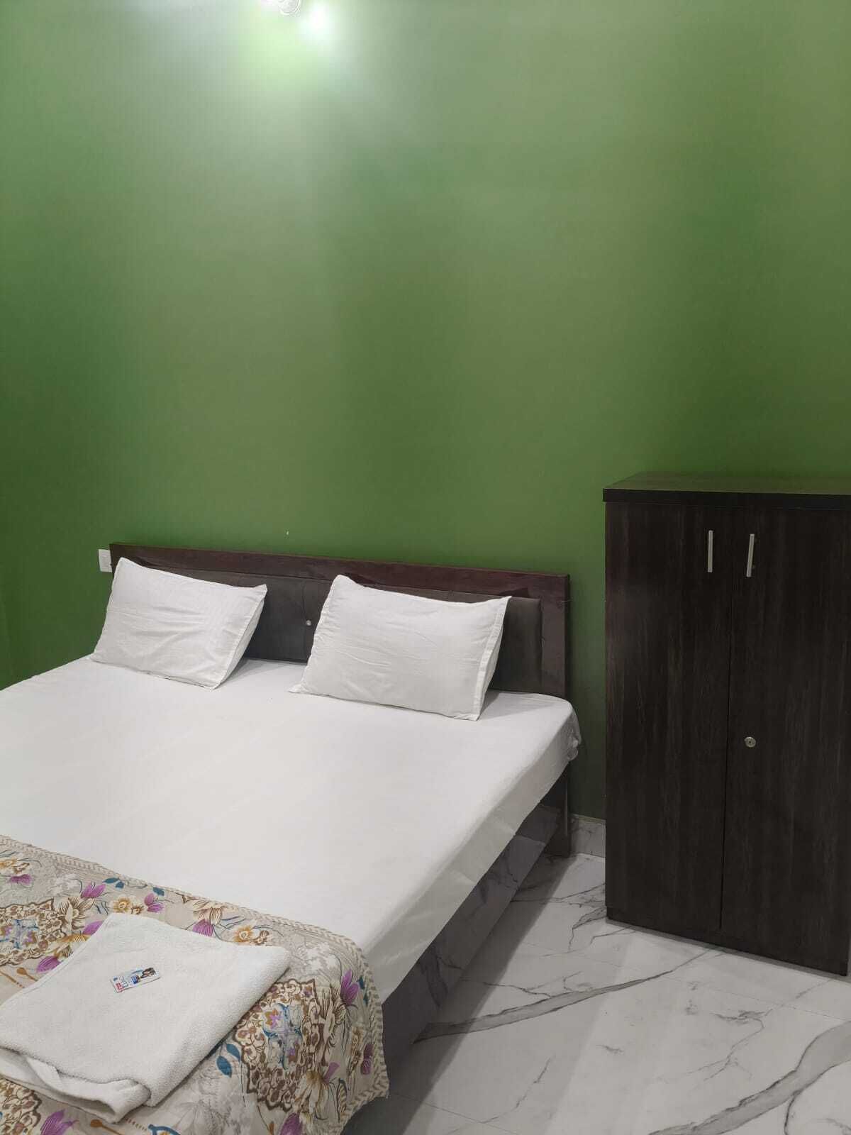A room with a bed, a wardrobe, and a green wall.