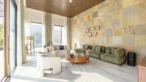 Un moderno salón con un ventanal grande, un ventilador de techo y una pared con diseño de piedra.