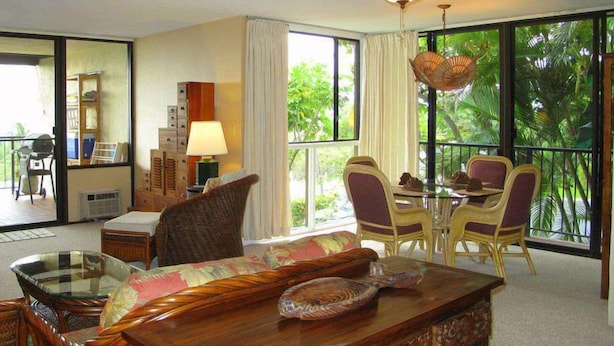 Quarto com mesa de jantar, cadeiras, ventilador de teto e grandes janelas.