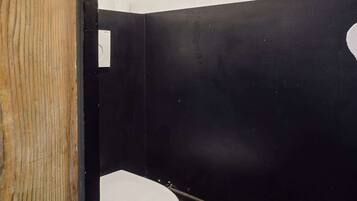 A small, narrow bathroom with a toilet, black and white checkered floor, and visible plumbing.
