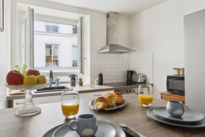 Eine moderne Küche mit Essbereich, ausgestattet mit einem Frühstücksangebot aus Croissants, Obst und Orangensaft.