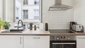 Una cocina moderna con horno integrado, extractor de acero inoxidable y ventana con vistas a un balcón.