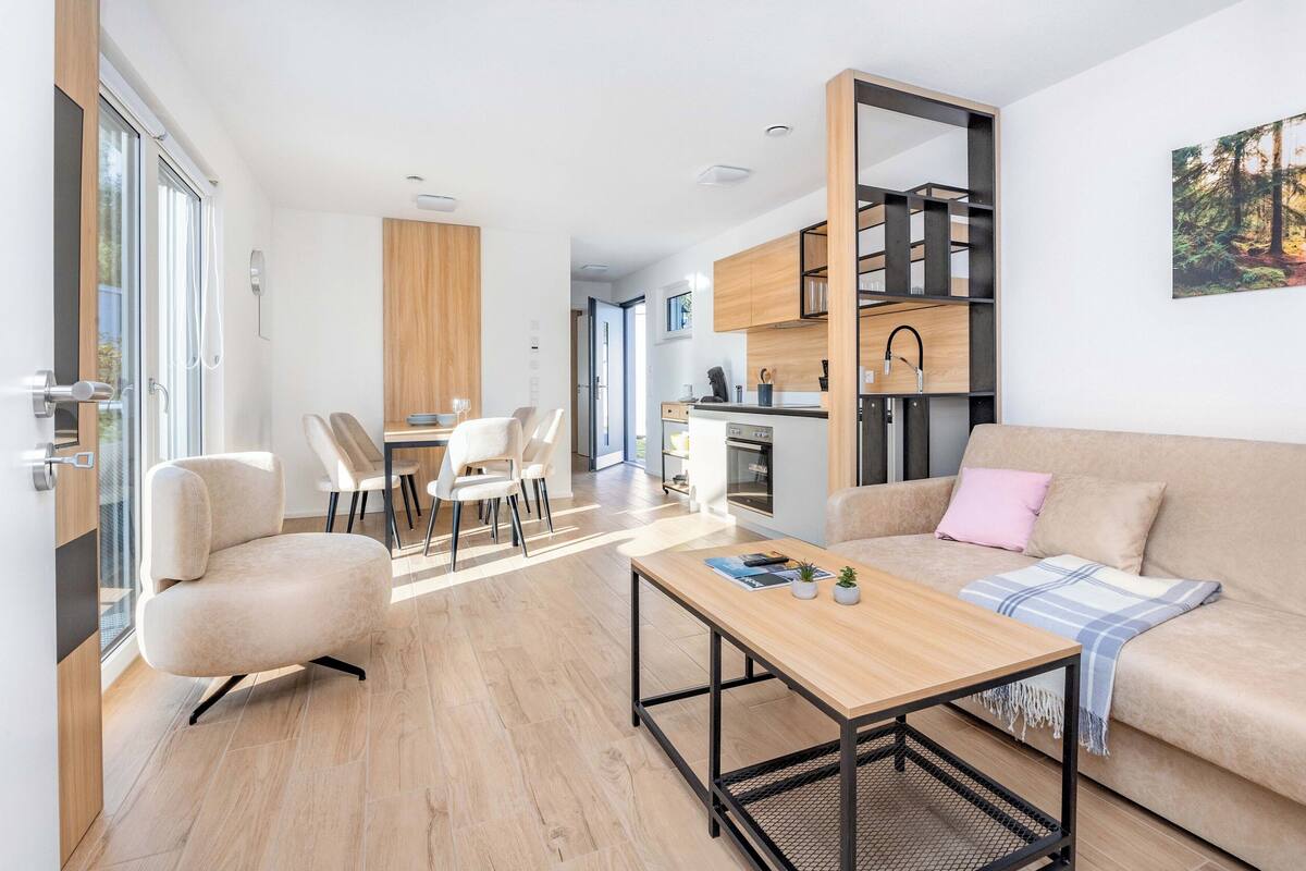 A modern living room with a sofa, a coffee table, and a dining area with chairs.