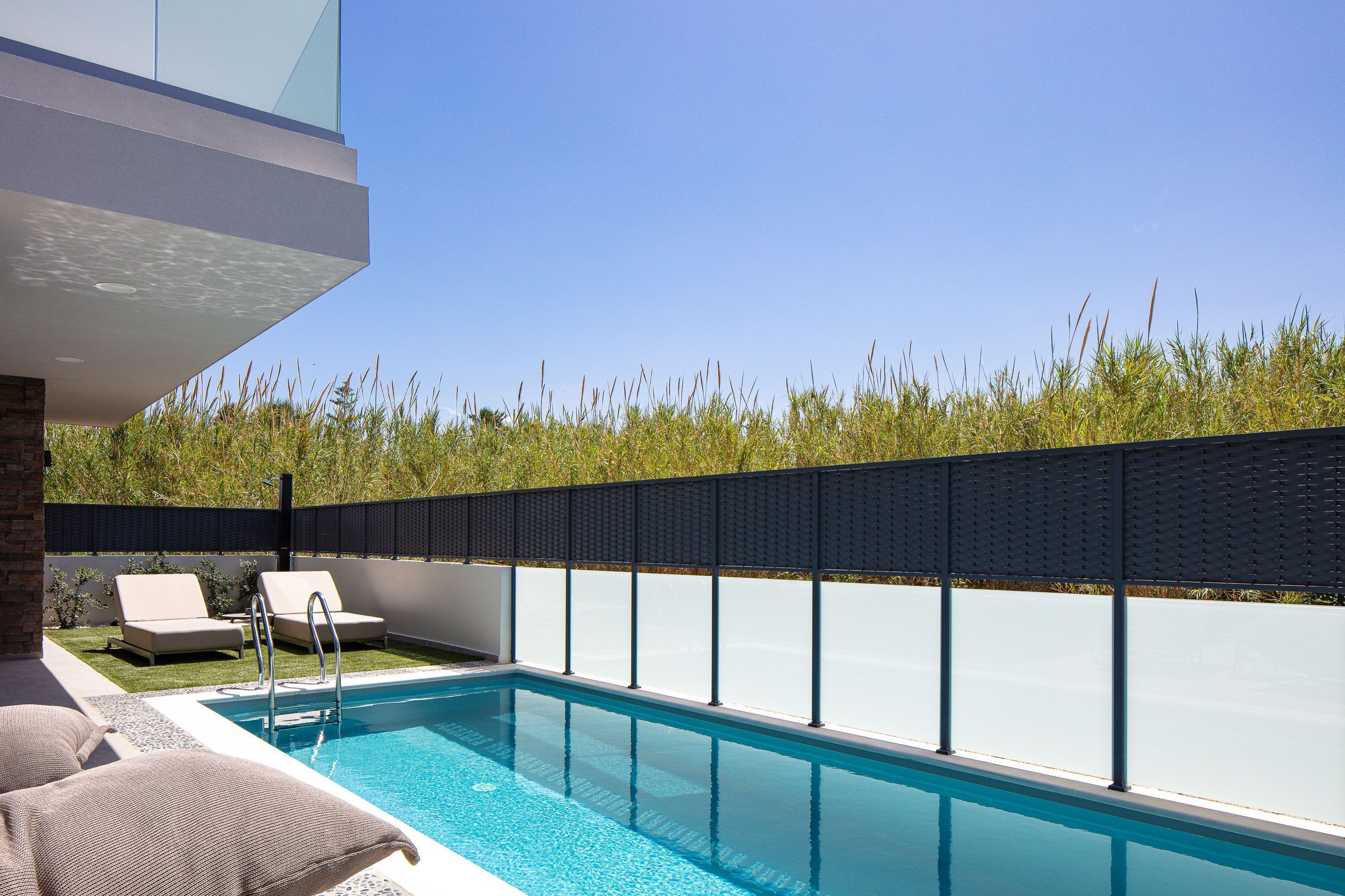 A modern outdoor pool area with two lounge chairs and a pool ladder.