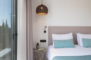 A hotel room with a bed, a bedside table with a plant, a wall-mounted light, and a view through a window. - Villasaints I Pool BBQ Walk to Beach (Chania)